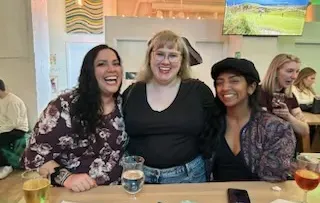 Three Mawrters smile together in a bar.